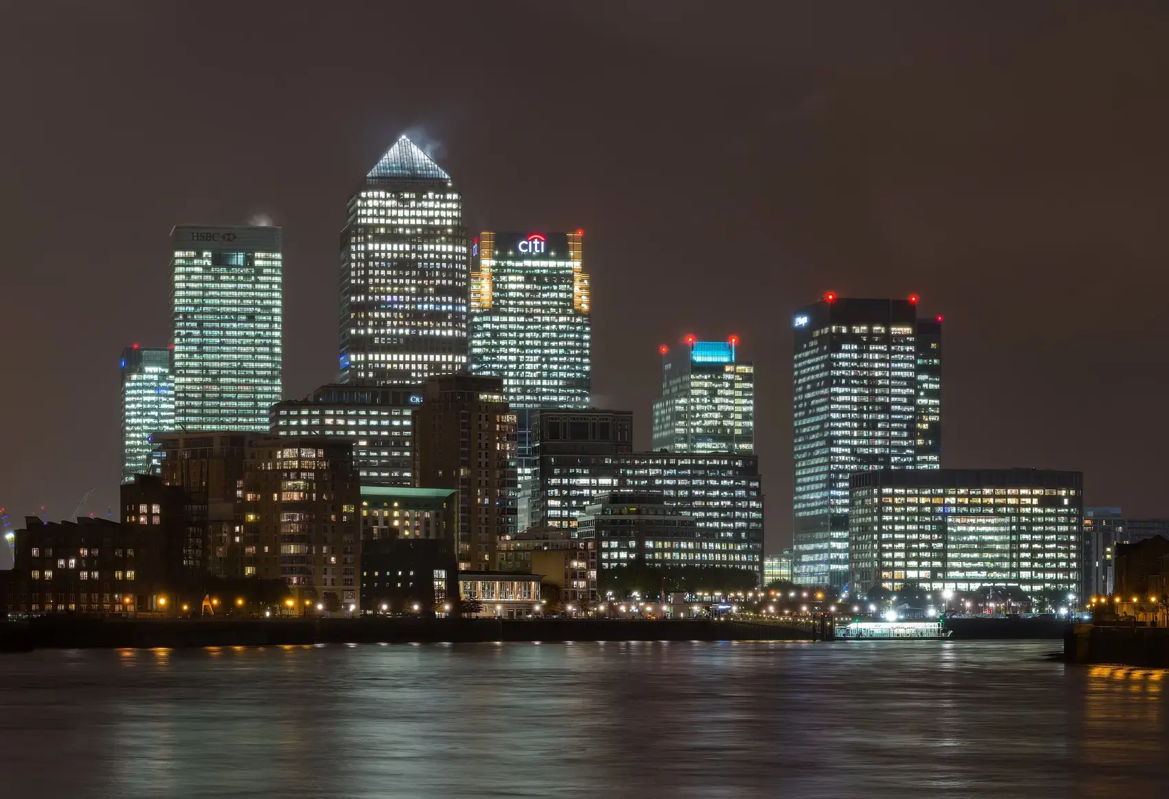 The towers of Canary Wharf lit at night across the Thames